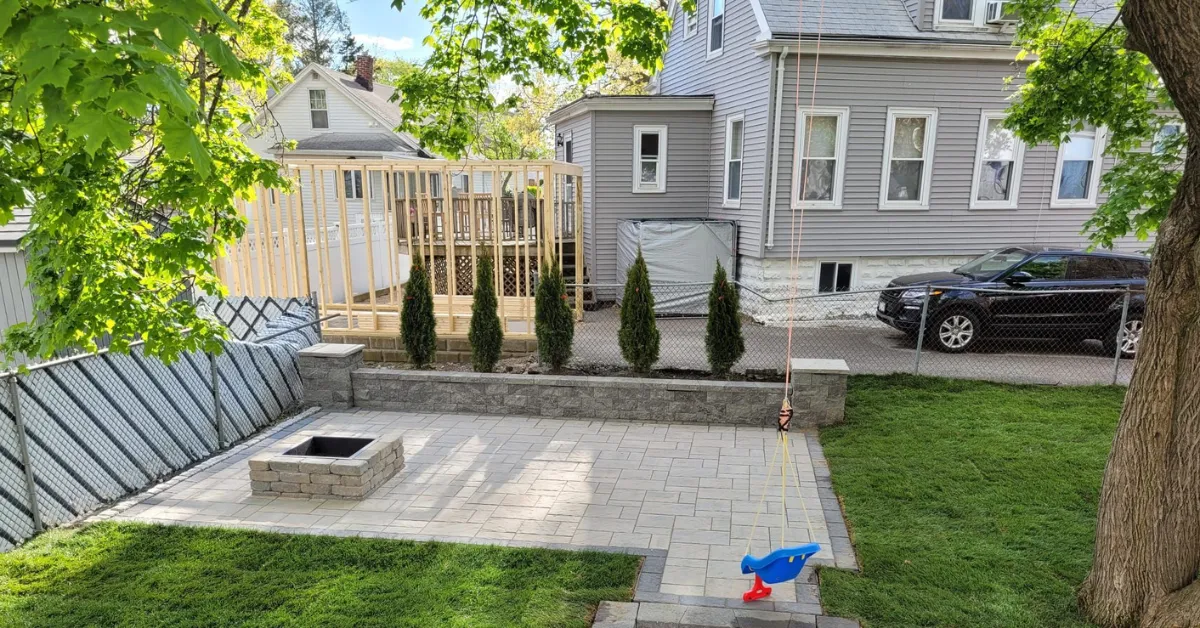 Custom stone patio installation in West Concord, MA backyard